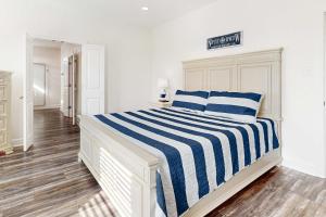 a white bedroom with a blue and white striped bed at The Anchor Holds in Dauphin Island
