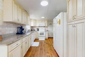 a kitchen with white cabinets and a white refrigerator at Macs Fish Camp in Dauphin Island +10 photos