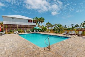 a swimming pool with chairs and a building at Bale Oasis in Dauphin Island