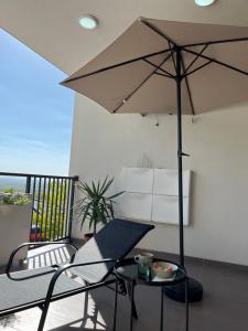 a patio with a table and an umbrella on a balcony at Cozy apartment Kosmaj Residence in Rogača