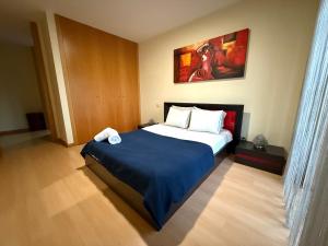 a bedroom with a large bed with a blue blanket at Sol Poente Praia Apartment in Apúlia