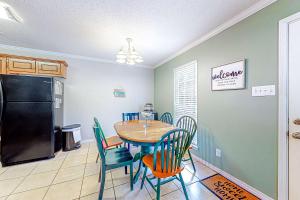 a dining room with a table and chairs and a refrigerator at Perfectly located condo with beach access - deck internet W&D & AC in Dauphin Island