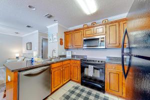 a kitchen with wooden cabinets and a stainless steel refrigerator at Perfectly located condo with beach access - deck internet W&D & AC in Dauphin Island
