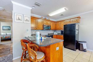 a kitchen with a black refrigerator and wooden cabinets at Perfectly located condo with beach access - deck internet W&D & AC in Dauphin Island