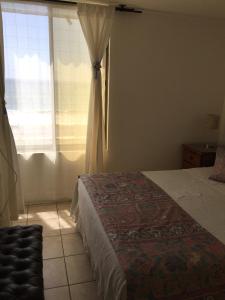 1 dormitorio con cama y ventana en Departamento Avenida Del Mar, en La Serena