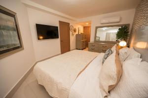 a bedroom with a white bed and a television at Caribbean Beachfront Resort in Puerto Plata +62 photos