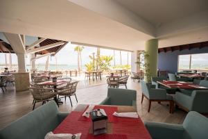 a restaurant with tables and chairs with a view of the ocean at Caribbean Beachfront Resort in Puerto Plata