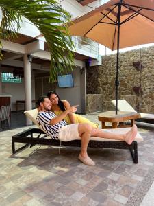 a man and a woman sitting in a chair under an umbrella at Horizonte del Mar Hotel Boutique in Santa Marta