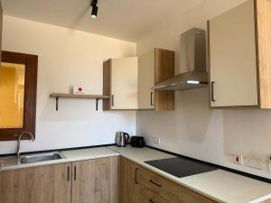a kitchen with wooden cabinets and a sink at Fort Chambray Gozo 2BDR Apartment in Għajnsielem
