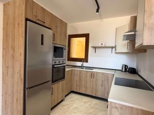 a kitchen with a stainless steel refrigerator and wooden cabinets at Fort Chambray Gozo 2BDR Apartment in Għajnsielem