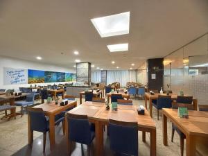 a restaurant with wooden tables and blue chairs at Hotel Golden Park Salvador By Nacional Inn in Salvador