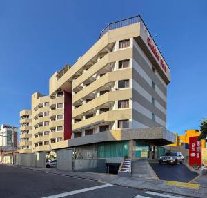 a large building with a car parked in a parking lot at Hotel Golden Park Salvador By Nacional Inn in Salvador