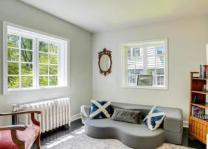 a living room with a couch and two windows at Swimming Under The Stars In The Historical District in Lynchburg