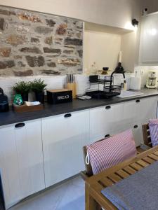a kitchen with white cabinets and a stone wall at Koumara Stone House in Koútsi