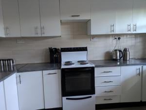 a kitchen with white cabinets and a black oven at Rehoboth Area 49 Guest House in Lilongwe
