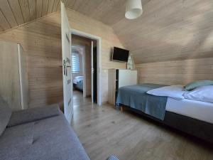 a bedroom with wooden walls and a bed and a tv at KANALOA in Pobierowo