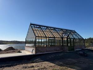 a glass greenhouse on the side of a body of water at Villa Krågenes - Hytte in Farsund
