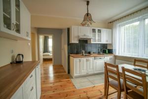 a kitchen with white cabinets and a wooden floor at ALE WIDOKI Apartamenty Gościnne in Giebło