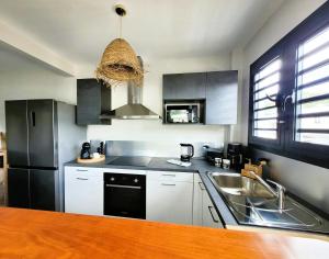 a kitchen with a sink and a refrigerator at Le léza - Terrasse et plage à 1 min in Les Trois-Îlets