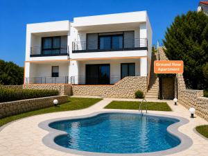 a villa with a swimming pool in front of a house at OlivaBeachHouse - Direct Waterfront & Mooring in Barbat na Rabu