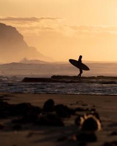 a person walking on the beach with a surfboard at Sines Surfmaroc in Tamraght Ouzdar