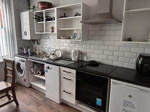 a kitchen with white cabinets and a black counter top at The Roost in Derry Londonderry