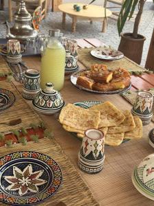 a wooden table with plates of food and plates of food at Sines Surfmaroc in Tamraght Ouzdar