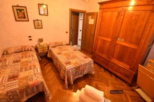 a room with two beds and a wooden cabinet at Affittacamere Casa Sofia in Anghiari