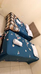 a bed with a blue comforter with flowers on it at Casa Mobiliada 4 camas e 2 quartos in Juazeiro do Norte