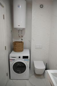 a white bathroom with a washing machine and a toilet at Apartment 84 in Donja Lastva