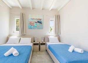 two beds in a room with two windows at Vivens Mykonos Studios & Suites in Ano Mera