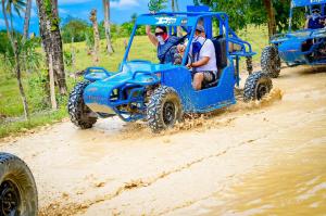 a group of people riding on a blue atv in the mud at Hotel casa inglesa in Buga