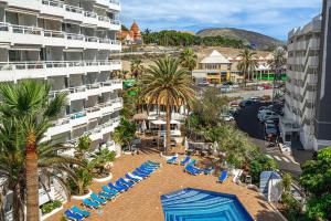 an aerial view of a resort with chairs and palm trees at Magic View Costa Adeje in Costa de Adeje
