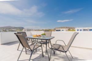 a table and chairs on a balcony with a view at Vivens Mykonos Studios & Suites in Ano Mera