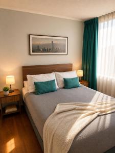a bedroom with a bed with two blue pillows at Departamentos Amoblados Torre Tagle in Santiago