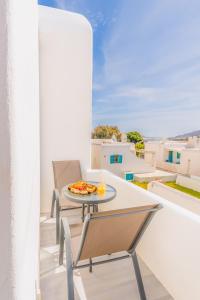 a table and chairs on a balcony with a pizza at Vivens Mykonos Studios & Suites in Ano Mera