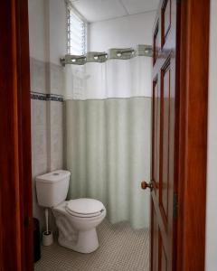 a bathroom with a toilet and a shower curtain at Casa Cultivo in Brisas de Zicatela