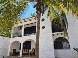 a palm tree in front of a white building at Casa Cultivo in Brisas de Zicatela