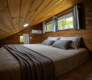 a bedroom with a large bed in a wooden room at Tiny House II - experiência de refúgio exclusivo in Gravataí