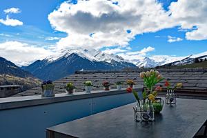 a table with flowers on a balcony with mountains at Ferienwohnung "Posta Veglia" - Cumbel in Cumbels