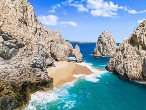 an aerial view of a beach between two large rocks at Modern 2BR Condo Close to Downtown Cabo in Cabo San Lucas