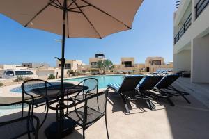 a patio with chairs and an umbrella next to a pool at Modern 2BR Condo Close to Downtown Cabo in Cabo San Lucas