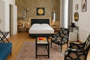 a hotel room with a bed and a chair and a table at Hotel La Baie Royale in Pontorson