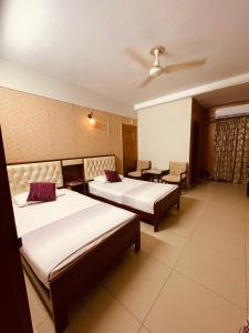 a hotel room with three beds and two chairs at Solo Hotel in Sargodha