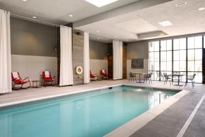 a swimming pool with chairs and a table in a building at Archer Hotel Florham Park in Florham Park