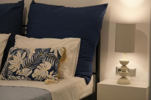 a bed with a blue and white pillow and a lamp at Antel apartment in Naousa