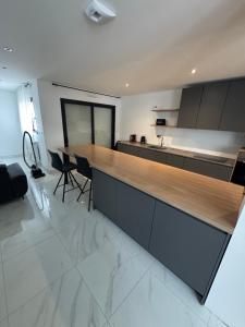 a large kitchen with a wooden counter and chairs at Maison proximité de la plage in Plouzané
