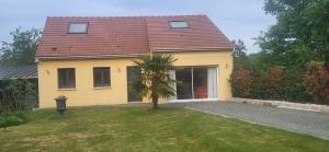 a yellow house with a palm tree in the yard at Maison au calme in Nogent-sur-Eure