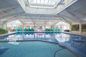 a large swimming pool with chairs in a building at Holiday Caravan Orchards Holiday Village in Brightlingsea