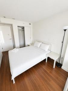 a white bed and a chair in a room at Moden & Cozy Downtown Condo in Vancouver in Vancouver